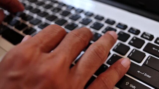 Close-up of hands typing on a laptop keyboard, capturing the motion and detail of everyday digital work. This scene represents productivity, communication, online activity, and modern technology use.