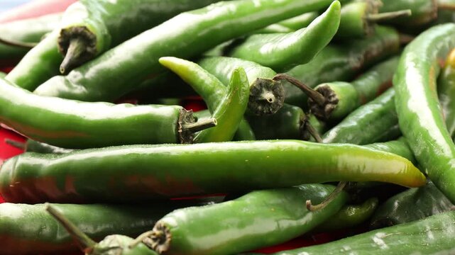 Fresh green chili peppers on red plate, closeup