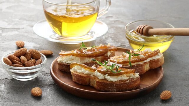 Woman pouring tea into cup and taking bruschetta with pear at grey table, closeup