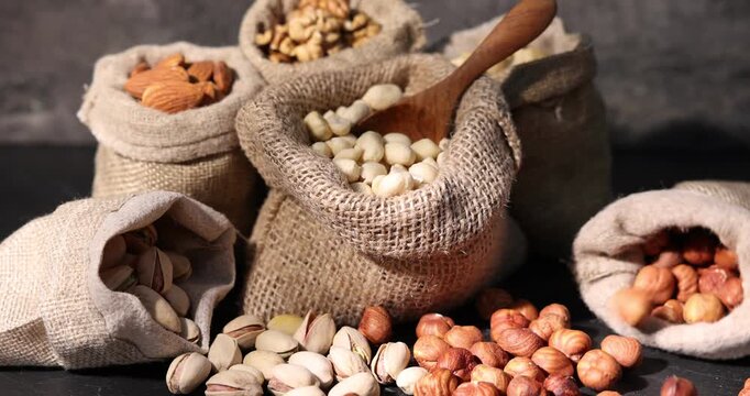 Different types of nuts in bags on black table, closeup