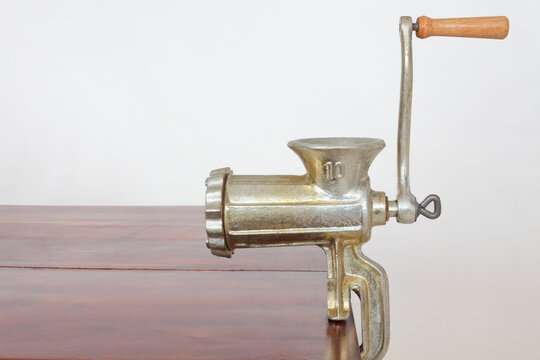 Vintage Manual Cast Iron Meat Grinder Clamped to Wooden Table   tool for food preparation and grinding.