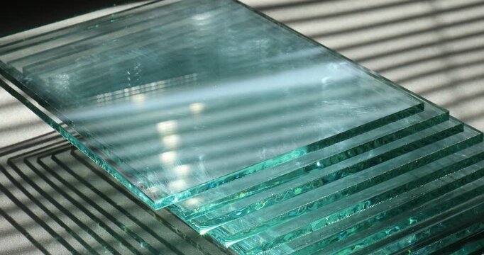 Stack of glass sheets on grey table, closeup. Camera moving up