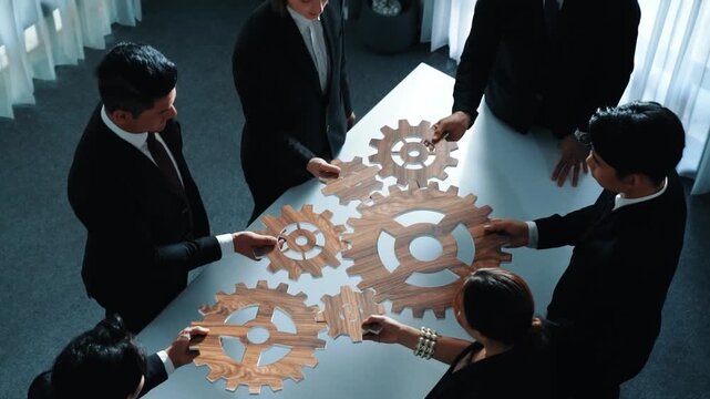 Top view of professional business team bring filled last cog to complete system. Group of smart diverse business people joining gear together at workplace.Show teamwork,unity, working. Directorate.