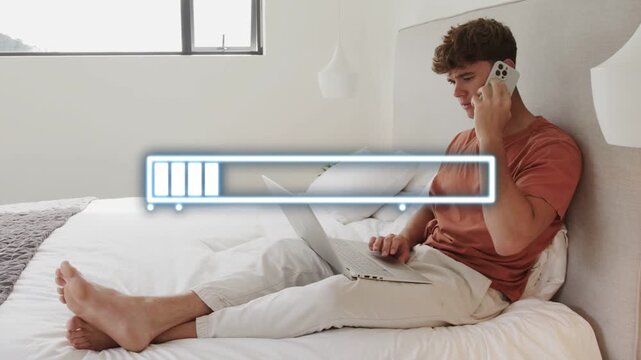 Man speaking on phone while tapping laptop, uploading project for remote work, progress bar filling