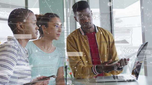 Man pointing at laptop and tapping tablet, women leaning in reviewing animated data overlays for UX