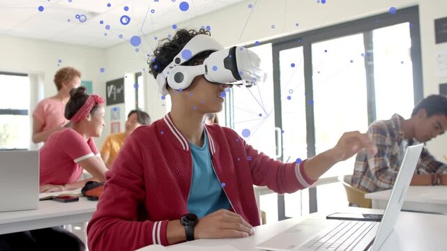 Teenage student putting on VR headset, gesturing, manipulating lesson on laptop with blue graphics