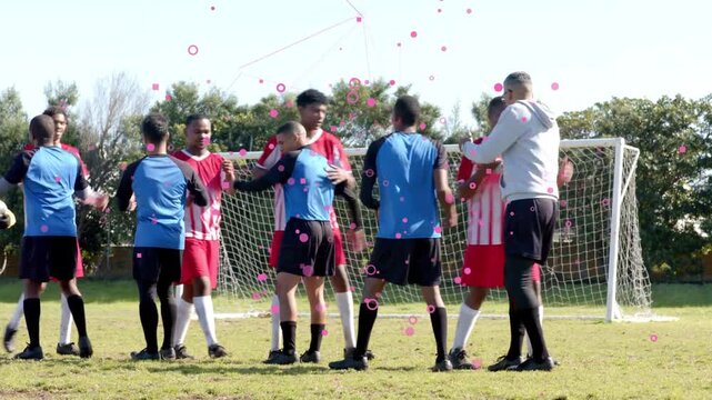 Teams shaking hands after whistle at goal coach patting showing sportsmanship pink dots over group