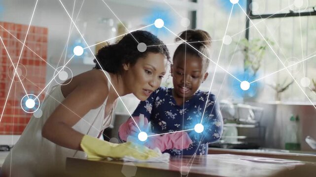 Mother demonstrating wiping kitchen counter teaching girl home cleaning while nodes animating hands
