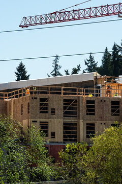 Major building commercial construction project, construction workers on top floor working on wood framing, multistory housing real estate development
