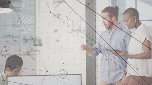 Two colleagues consulting tablet, pointing at monitor, aligning design while network overlay moving