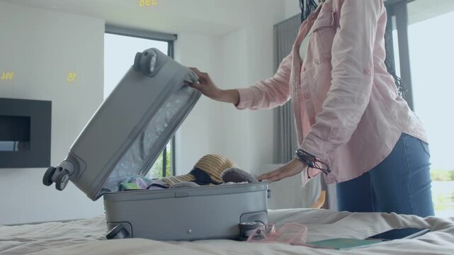 Woman getting travel alert, packing suitcase on bed while animated checklist guiding choices