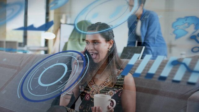 Seated woman holding mug taking business call, HUD graphics sweeping while colleagues smiling