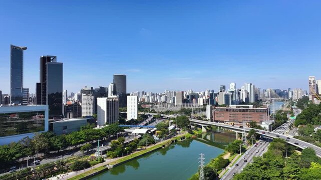 S&atilde;o Paulo skyline with Marginal Pinheiros and river, showing urban landscape, highways, bridges and modern buildings under clear blue sky.