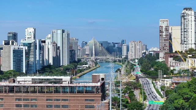 S&atilde;o Paulo skyline with Marginal Pinheiros and river, showing urban landscape, highways, bridges and modern buildings under clear blue sky.