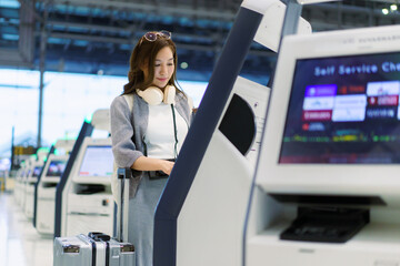 Asian woman using airport self service check in kiosk © DG PhotoStock