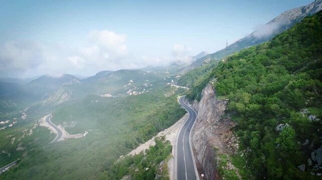 Man riding motorcycle in mountains with beautiful roads and clouds