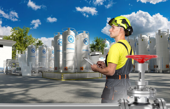 Hydrogen plant technician inspects storage tanks and pipeline valve at clean energy facility.