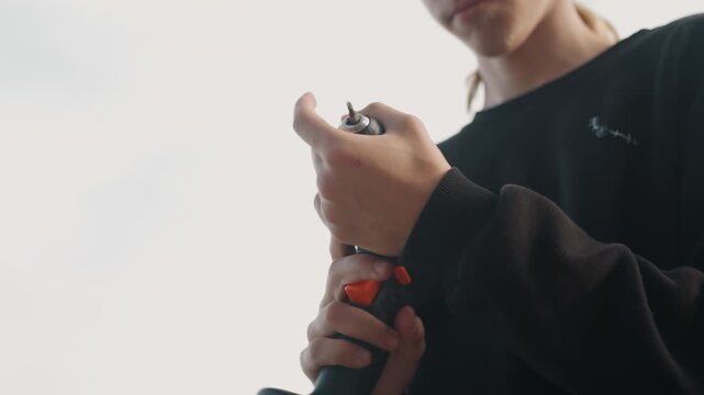 Young maker tightening drill chuck outdoors, closeup on hands and trigger, confident steady movements, prepping tool for build, bright sky background, cinematic framing, tactile focus