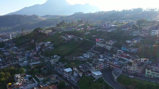 Otavalo, Ecuador: 5-1-2023: aerial view over a hill with houses when the sun is going under behind