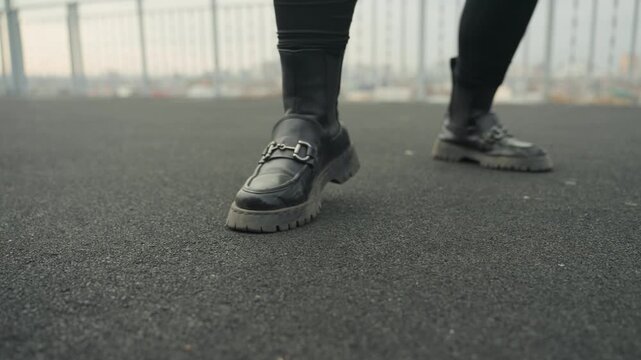 Feet dancing overhead. Dancing feet on rooftop surface. Feet in leather shoes performing dance on city roof. Footsteps in dark shoes creating rhythmic motion against urban skyline backdrop
