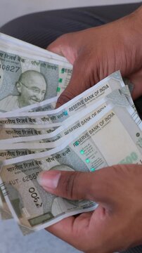 Close up of a man counting 500 Rupee Indian currency notes