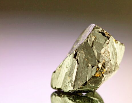 Macro photography of a raw metallic ore mineral with a crystalline structure and its reflection.