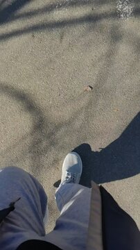 OV walking on sunny asphalt, focusing on white sneakers