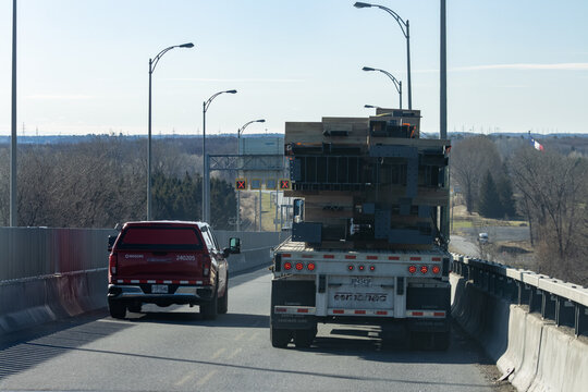 Quebec, Canada, 24 April 2026 : A Rogers pickup truck and a Cormac semi-truck transport large metal structures on a bridge.