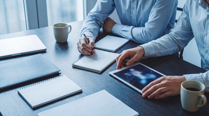 Professional business colleagues focused on tasks during a collaborative meeting. © Jonathan