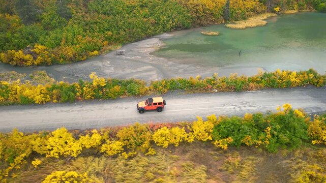 Aerial view of an off road vehicle driving on a country road in Alaska during autumn
