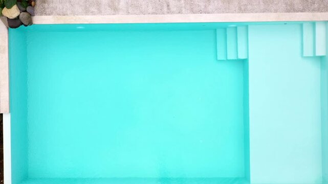 Blue water of a tropical clear blue swimming pool, zooming out to reveal the forest environment alongside