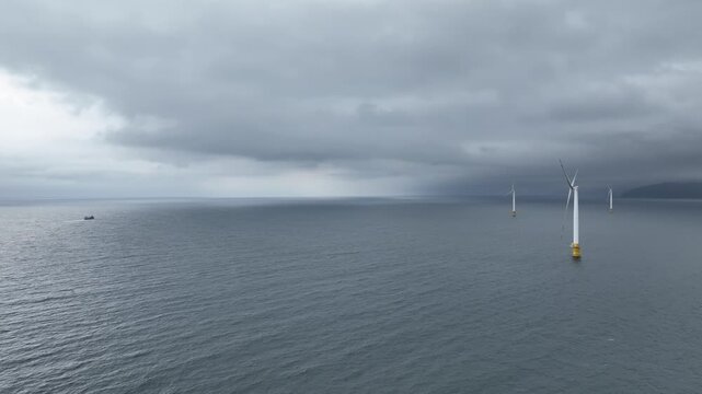 悪天候の四月下旬、北風をうけて回転する富山県の下新川海岸に設置されている洋上風力発電風車