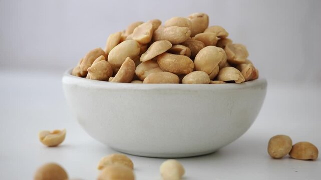 Eating roasted peanuts in a simple bowl at home