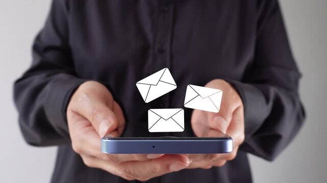 Close-up of a woman's hands holding a mobile phone with an animation of several mail envelopes being lifted upwards. Arrival of several emails