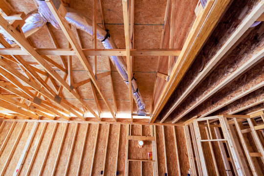Wooden beams, ductwork are part of construction of new house ongoing building work inside.