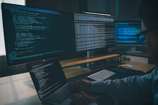 Developing programmer Website design at a multi monitor workstation with laptop and screens displaying scripts, showing web development, coding, software workflow, and technical productivity in dark o
