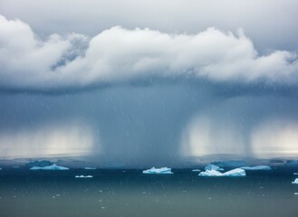 Obraz premium Heavy rainfall falling from dense clouds over a cold polar ocean with floating icebergs for seasonal weather forecast graphics, cinematic backdrop and climate news