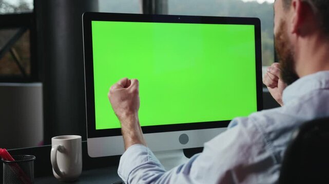 A focused man is typing away on his computer while surrounded by a vibrant green screen background