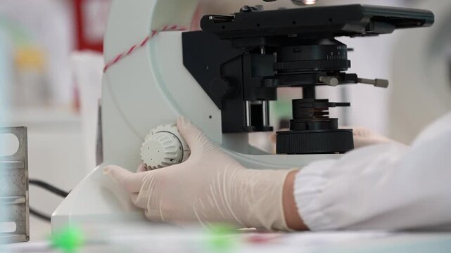 Laboratory Microscope Gloved Hand Medical Research Science Lab Optical Instrument White Glove Laboratory Equipment Close Up Focus Adjustment Medical Analysis Clinical Research Scientist Hand