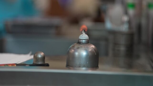 Laboratory alcohol burner metal burner small flame science lab chemistry equipment glassware table close up silver burner test room bench top gloved hand glass tube safety glove heating device