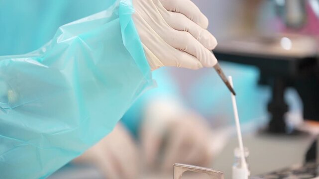 Gloved hand laboratory test tube clinical sample transfer with latex glove and pipette medical research analysis in sterile medical lab bench workflow