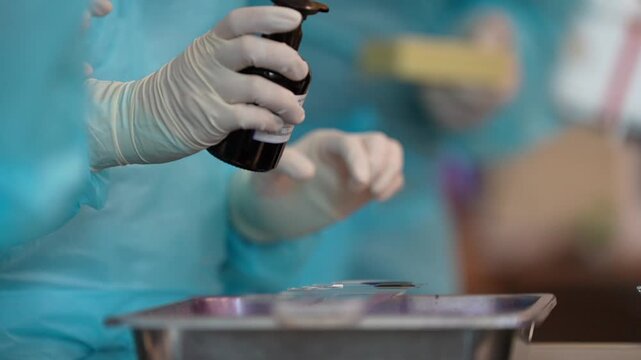 Gloved hand staining slide in laboratory with medical technician preparing sample on tray for clinical pathology analysis and stain bottle liquid dropper microslide workflow