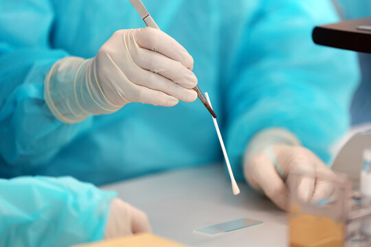Laboratory testtube gloved hand cotton swab medical test laboratory work clinical sample sterile tool blue gown research table science lab