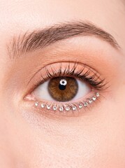 Obraz premium Macro of a single human eye with tiny crystal rhinestones glued along lower lash line, surreal editorial beauty