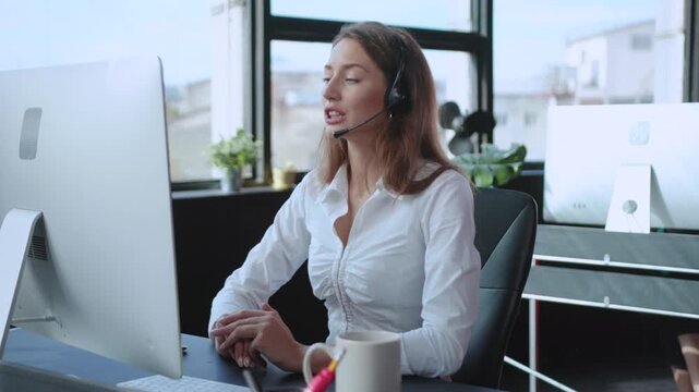 A woman utilizing a headset while performing remote work activities in a modern office setting