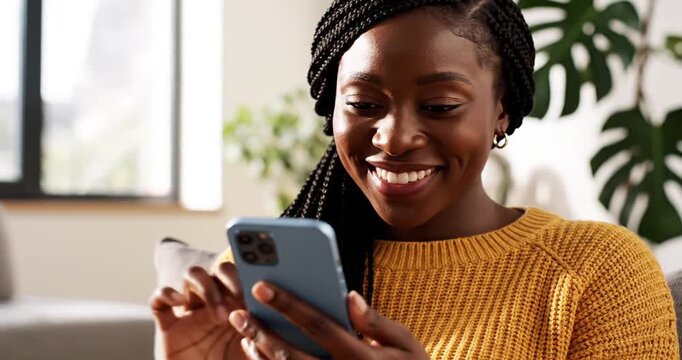 Woman with braided hair in a cozy sweater engaging with her smartphone indoors