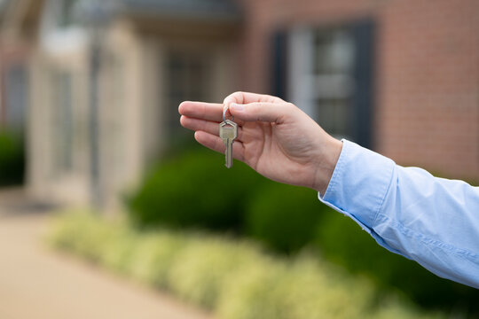 A realtor hands the keys after finalizing a property purchase. Homeowner holds keys to newly purchased apartment. A real estate agent shows house keys. Client receives keys for a property.
