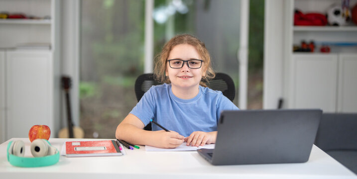 Child learning at home with laptop and books. Kid learning in a cozy home classroom. Kid learning homework. Online learning. Education concept. Child tutoring at home. Boy doing schoolwork.