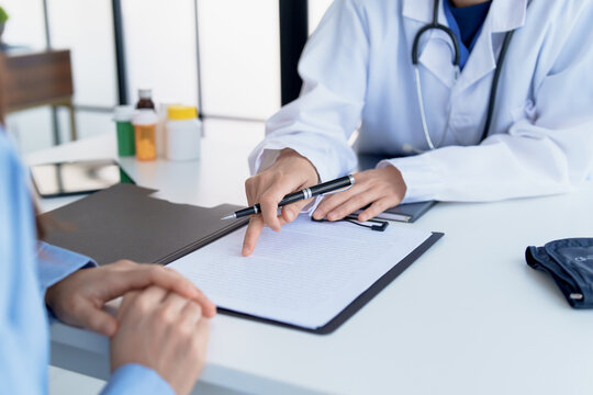 Doctor explaining treatment plan and obtaining informed consent while patient signing consent form in hospital.