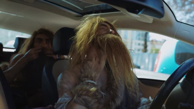 A humorous comedy scene featuring characters humorously dressed as cavemen while driving a car